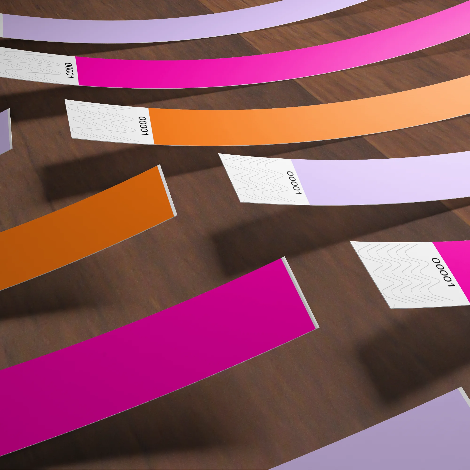 DIY laser printable wristbands in pink, orange and lavendar base colours on wood table close up