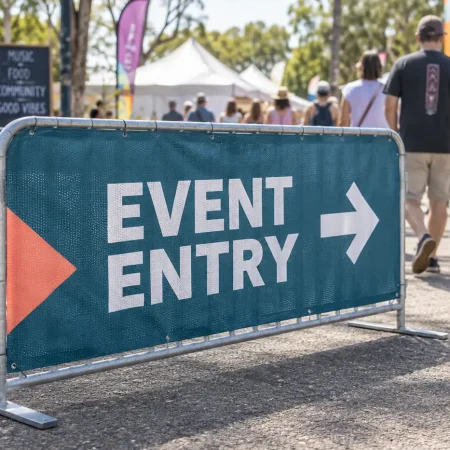 Teal printed mesh cover on a metal crowd-control barrier beside a festival entry route