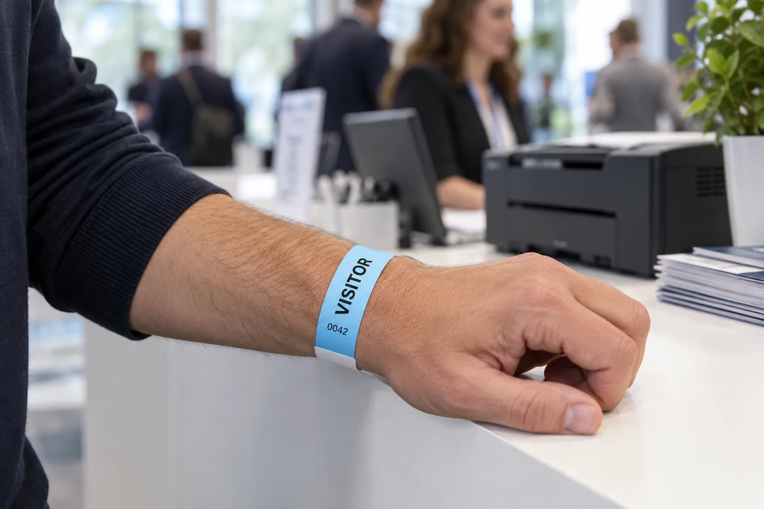 Conference guest wearing a light blue laser-printable wristband with a white adhesive end.